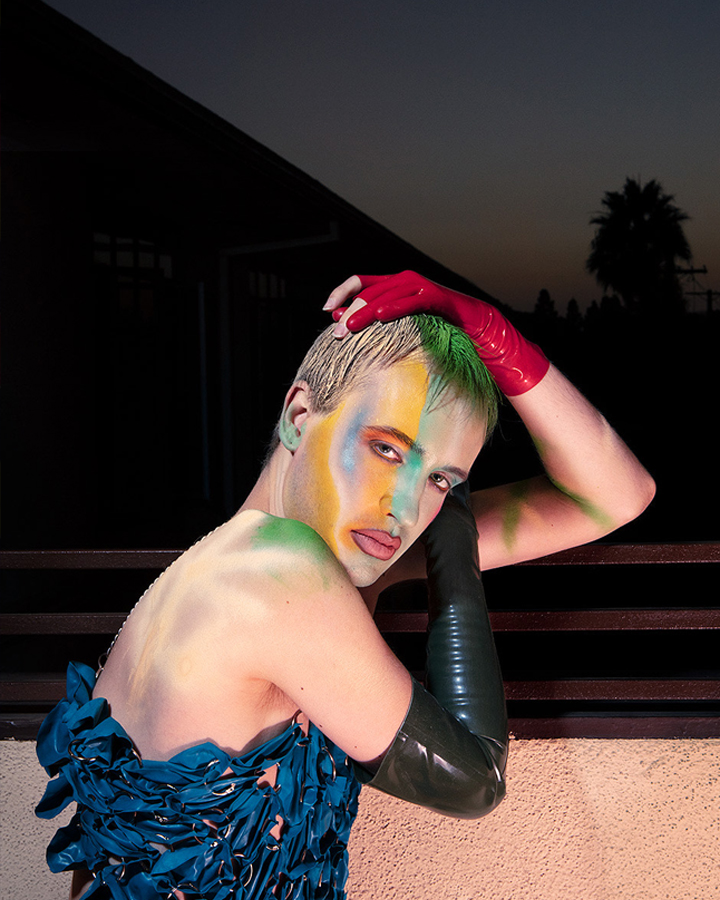 Jesse Clark posing on a balcony at sunset with colrful abstract face paint.